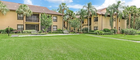 A hotel with multiple-story buildings, a well-maintained lawn, and palm trees.