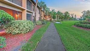 A hotel corridor with a concrete walkway, palm trees, and well-maintained lawns. - Alhambra Villas by Coolvacay (Kissimmee)