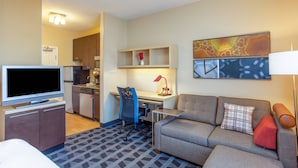 A hotel room with a TV, sofa, desk, chair, kitchenette, and a map on the wall. - TownePlace Suites by Marriott Huntsville (Huntsville)