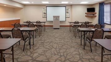 A conference room with a projector screen, a podium, and a television on a stand.