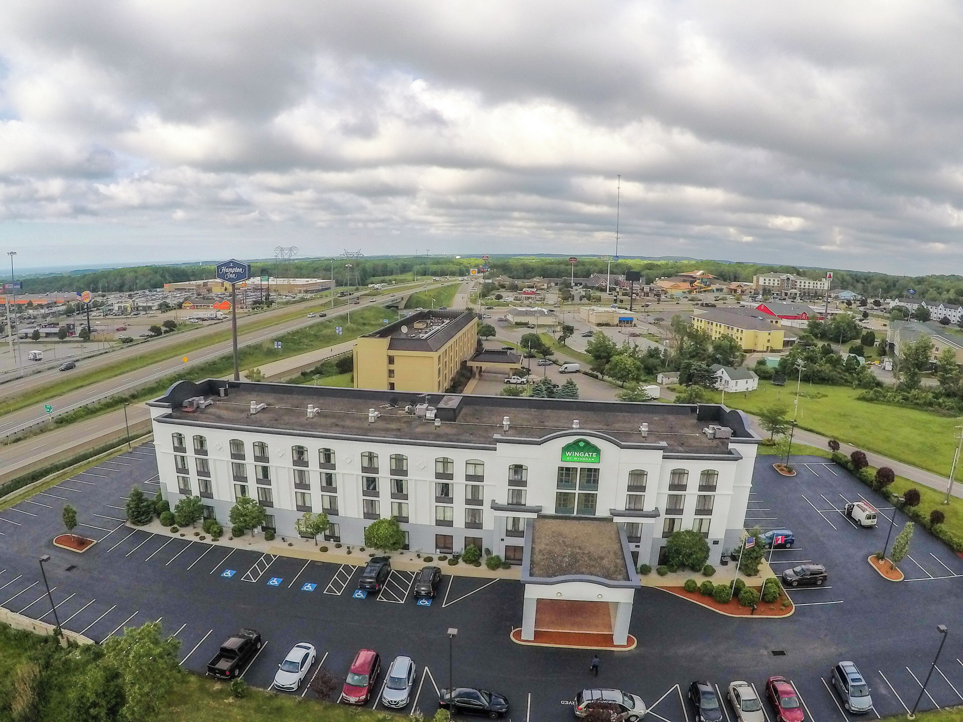 A large hotel with a central entrance, parking lot, and surrounding buildings.