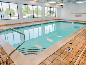 An indoor swimming pool with clear water, a tiled deck, and a windowed wall. - Wingate by Wyndham Erie (Erie)