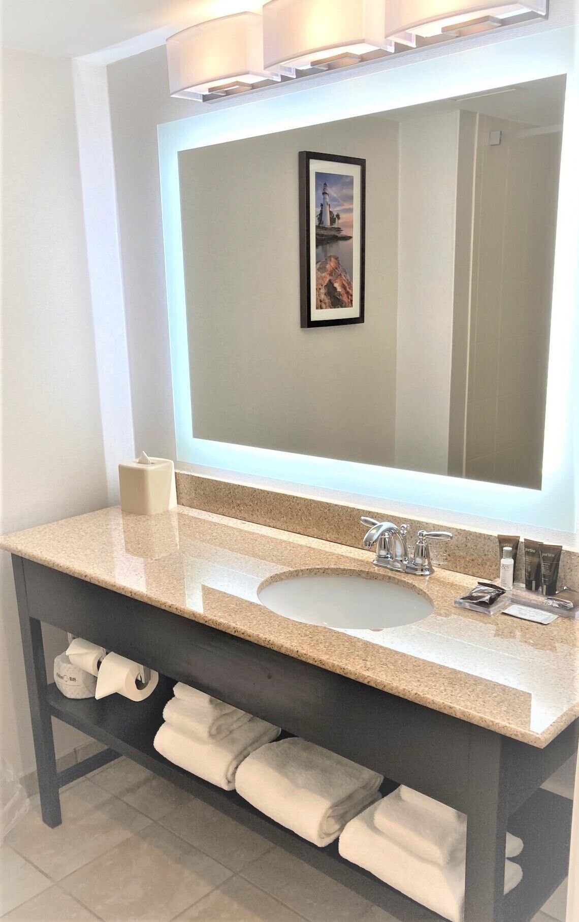 Un baño con un espejo grande, un lavabo y un perchero para toallas.