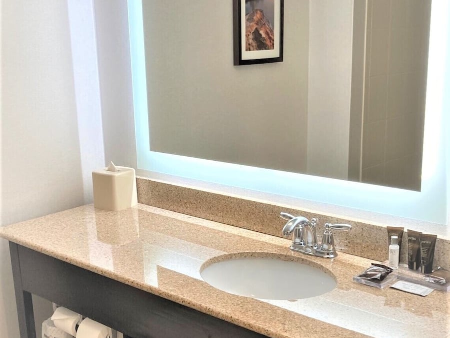 Un baño con un espejo grande, un lavabo y un perchero para toallas.