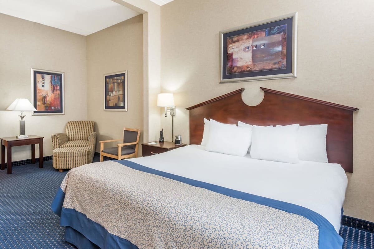 Una habitación de hotel con una cama grande, dos sillas, un escritorio y dos lámparas.