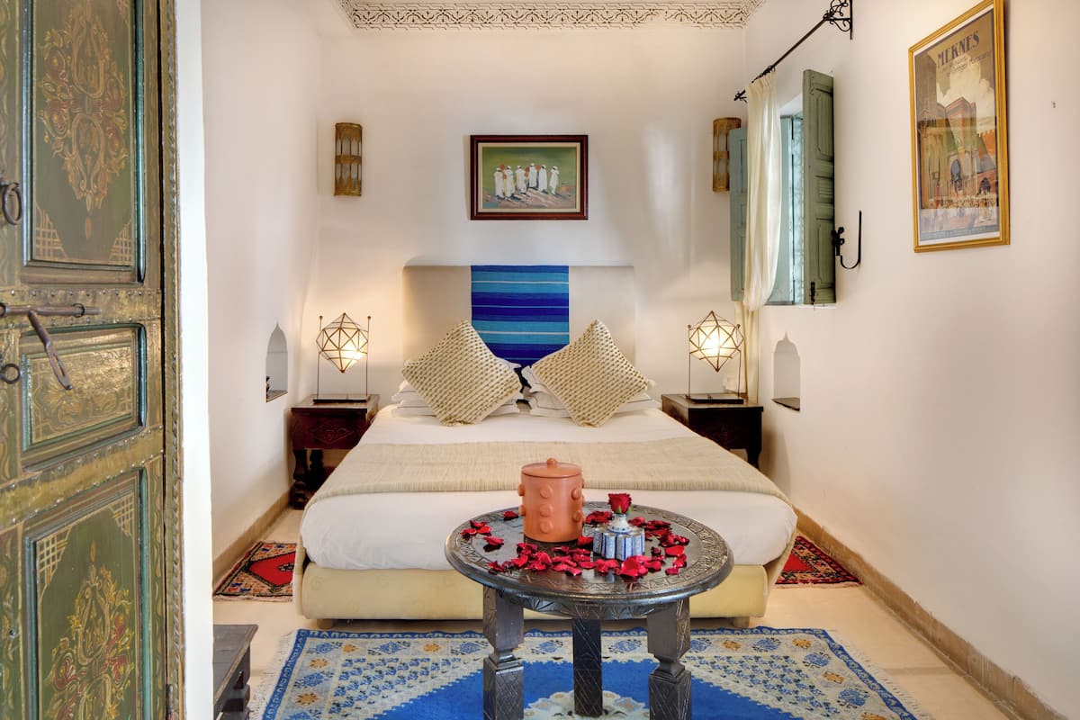 Une chambre d’hôtel avec un lit, une table ronde ornée d’une bougie et une décoration murale bleue et blanche à rayures.