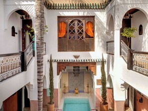A courtyard with a pool, arches, and potted plants.