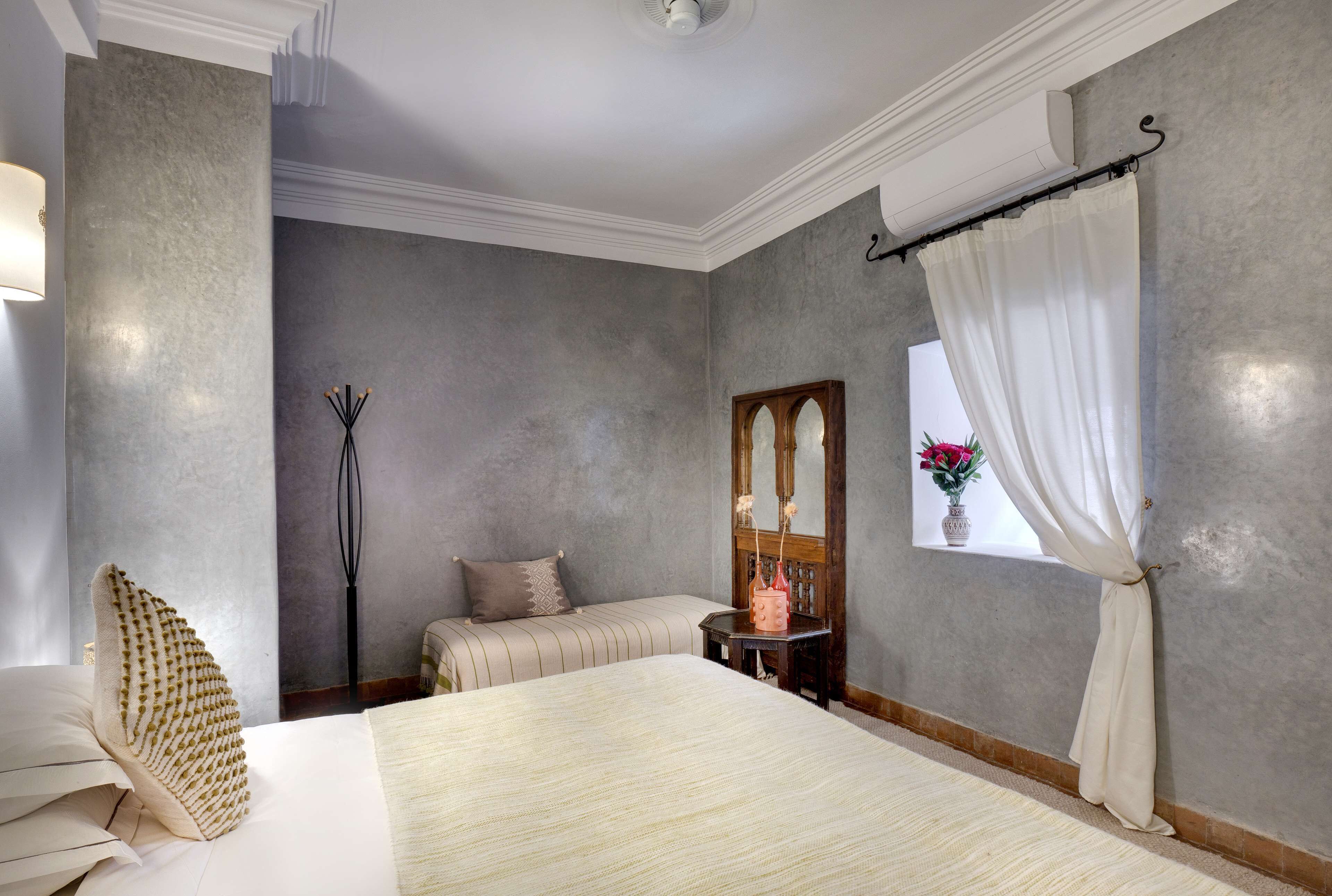 Habitación de hotel con una cama grande, una mesita de noche, un espejo y una ventana con cortinas.