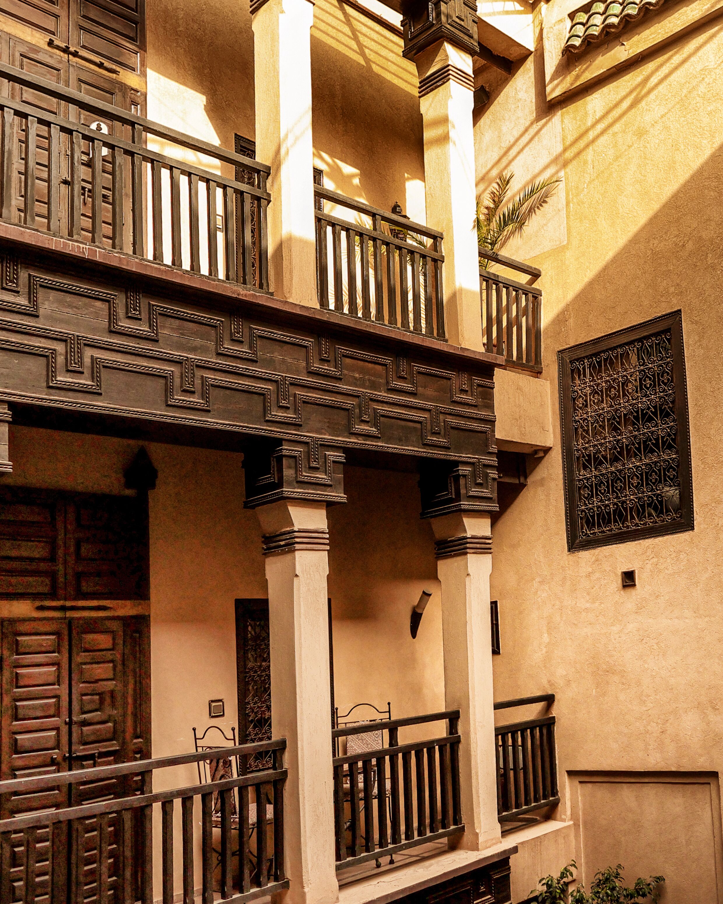 Un edificio tradicional con balcón, puertas de madera y barandillas de hierro decorativo.