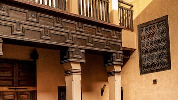 Un edificio tradicional con balcón, puertas de madera y barandillas de hierro decorativo.