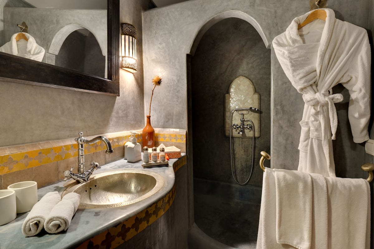 Une salle de bain équipée d’un lavabo, d’un miroir, d’un porte-serviettes et d’une douche.