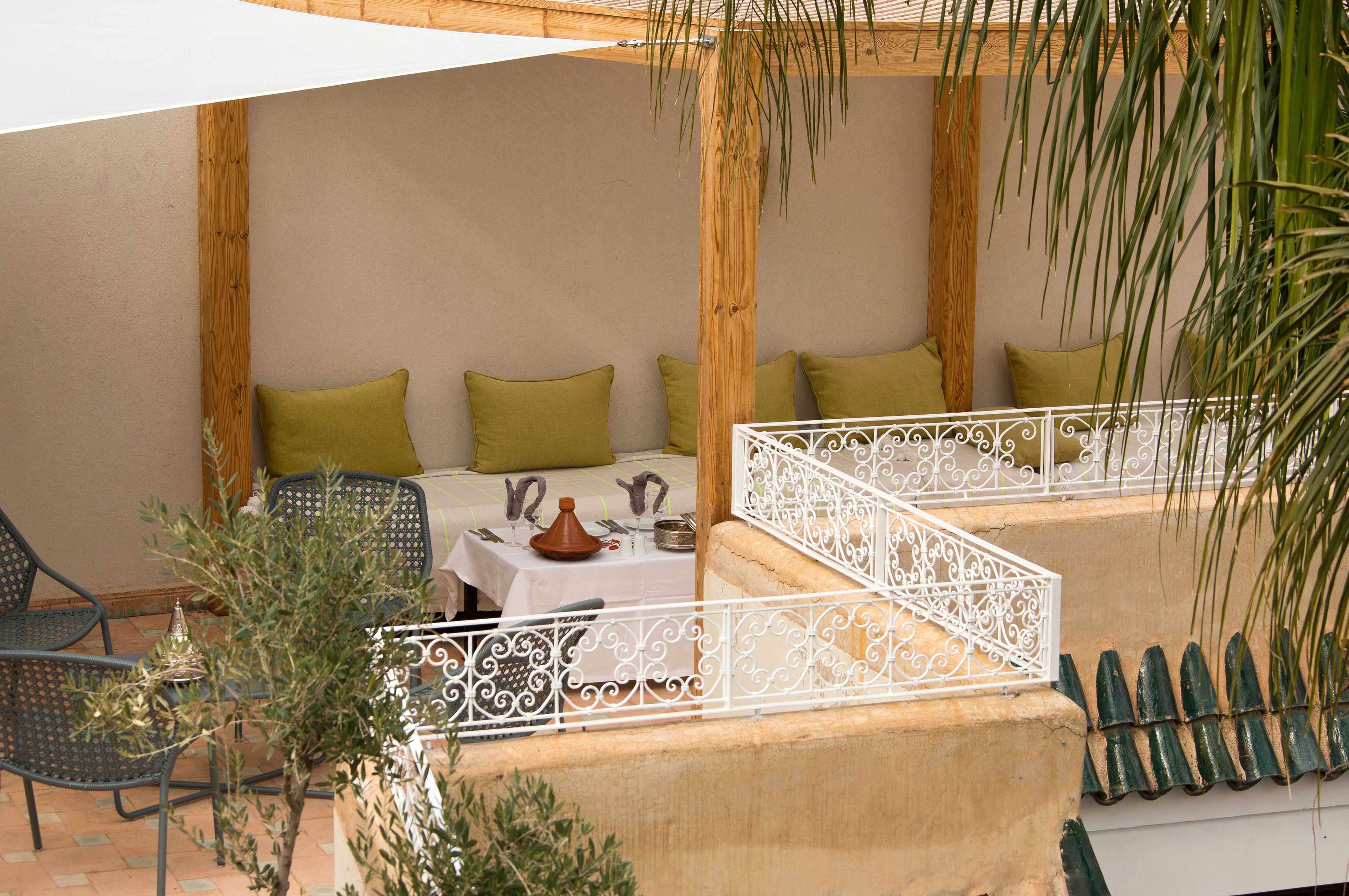 Un espace extérieur aménagé avec une table pour deux personnes, entouré de chaises et de coussins.