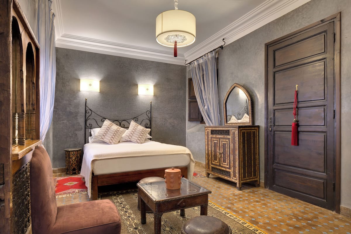 Une chambre à coucher comprenant un lit, une table de chevet, une chaise, une armoire et un miroir.