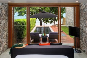 Un dormitorio con un ventanal grande, una cama, un televisor y vistas a una piscina y jardín.