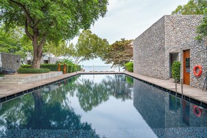 Una piscina con paredes de piedra y vistas al mar.