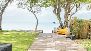 A wooden pathway leading to a beach with a yellow kayak and a green flag.
