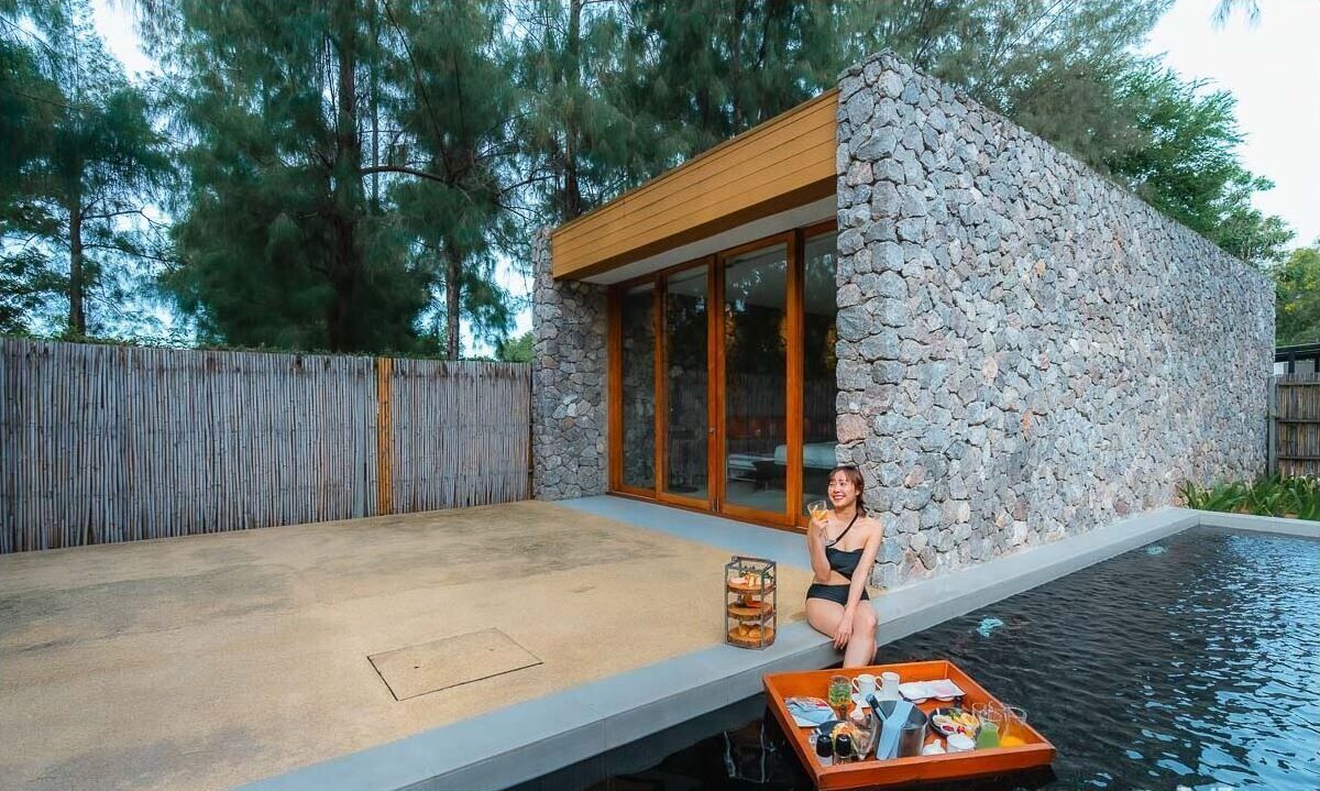 Una casa moderna con fachada de piedra y ventanas amplias, piscina y terraza de madera.