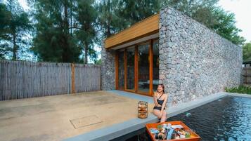 Una casa moderna con fachada de piedra y ventanas amplias, piscina y terraza de madera.