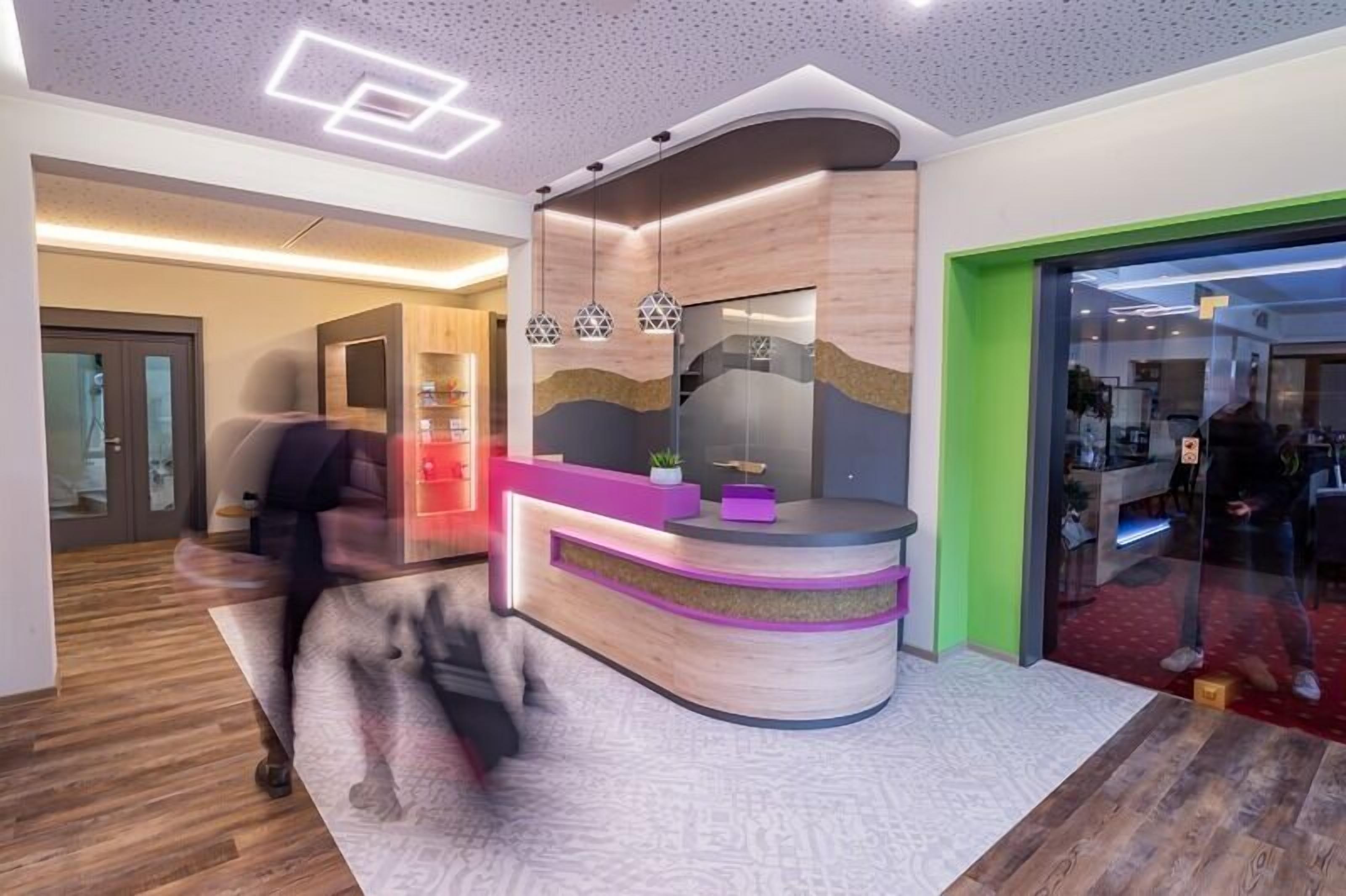 A modern reception area with a curved desk, a glass partition, and a wooden accent wall.