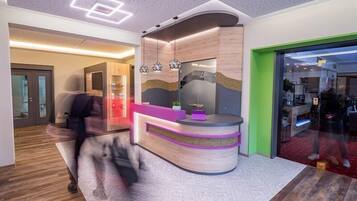 A modern reception area with a curved desk, a glass partition, and a wooden accent wall.