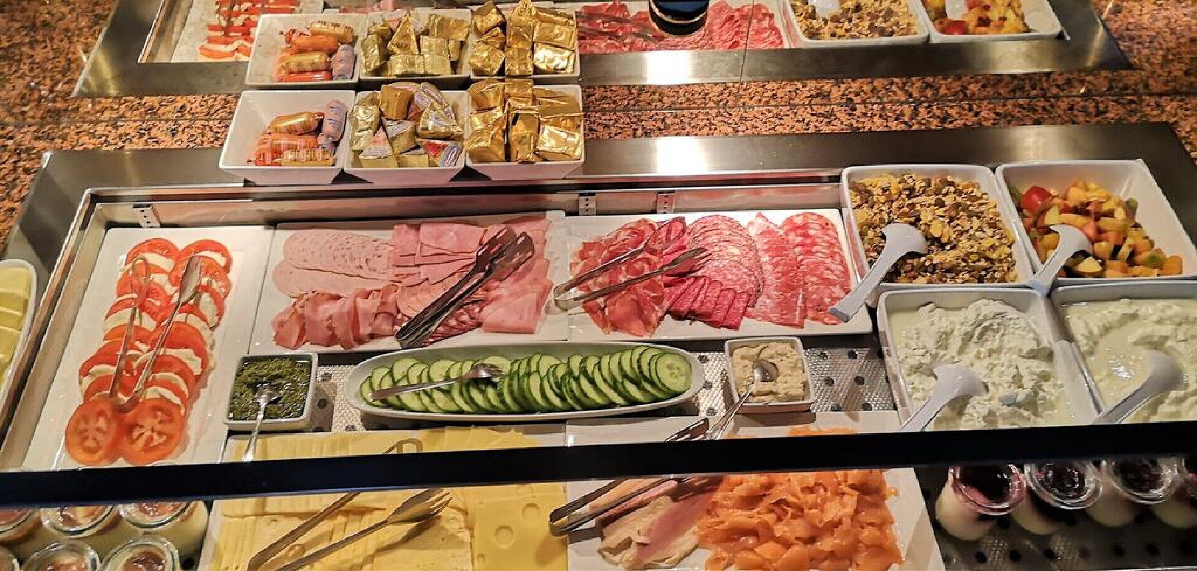 Un buffet con diversi cibi, tra cui salumi, formaggi e frutta.