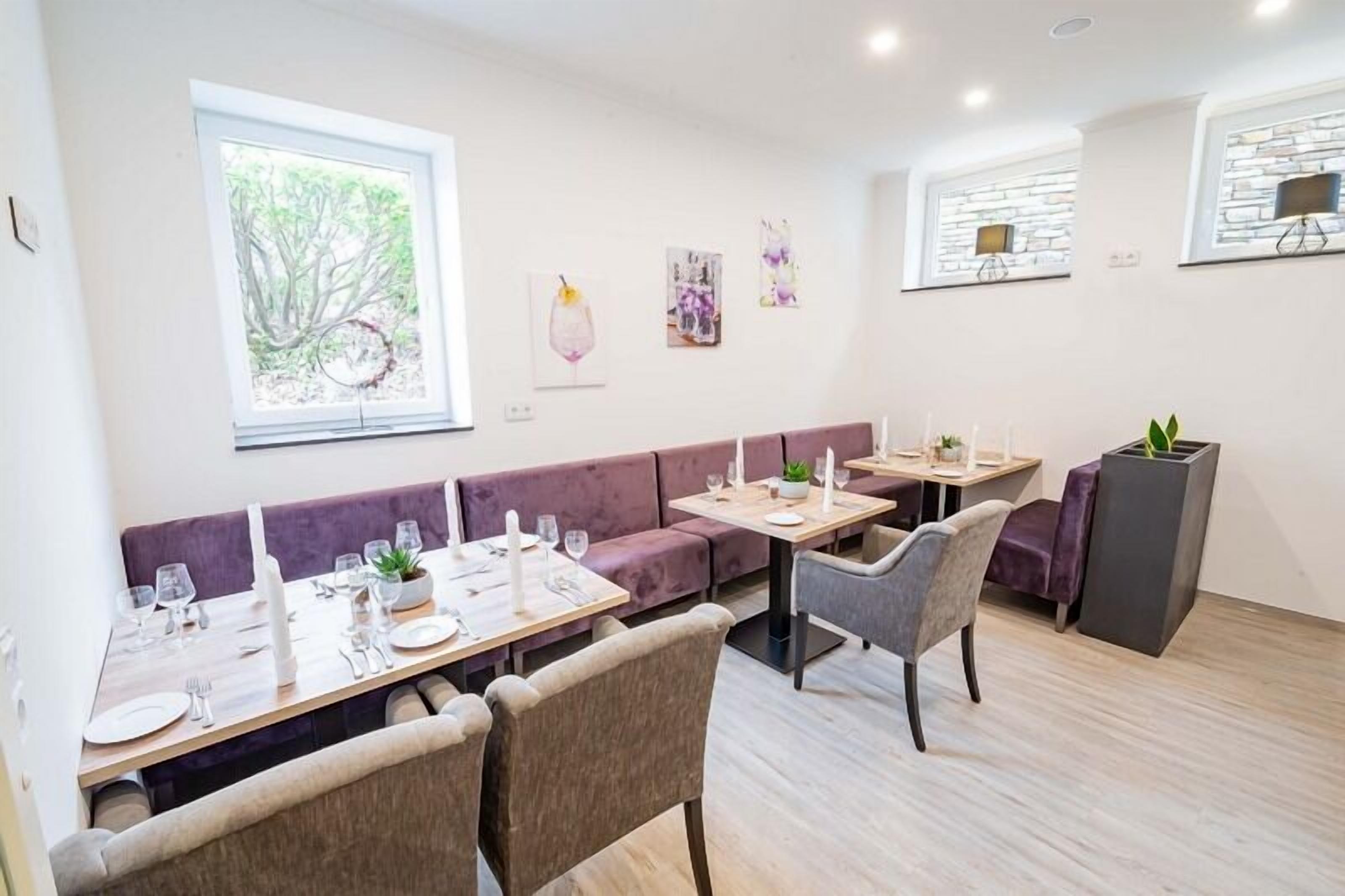 A modern dining area with a long table, cushioned seating, and artwork on the walls.