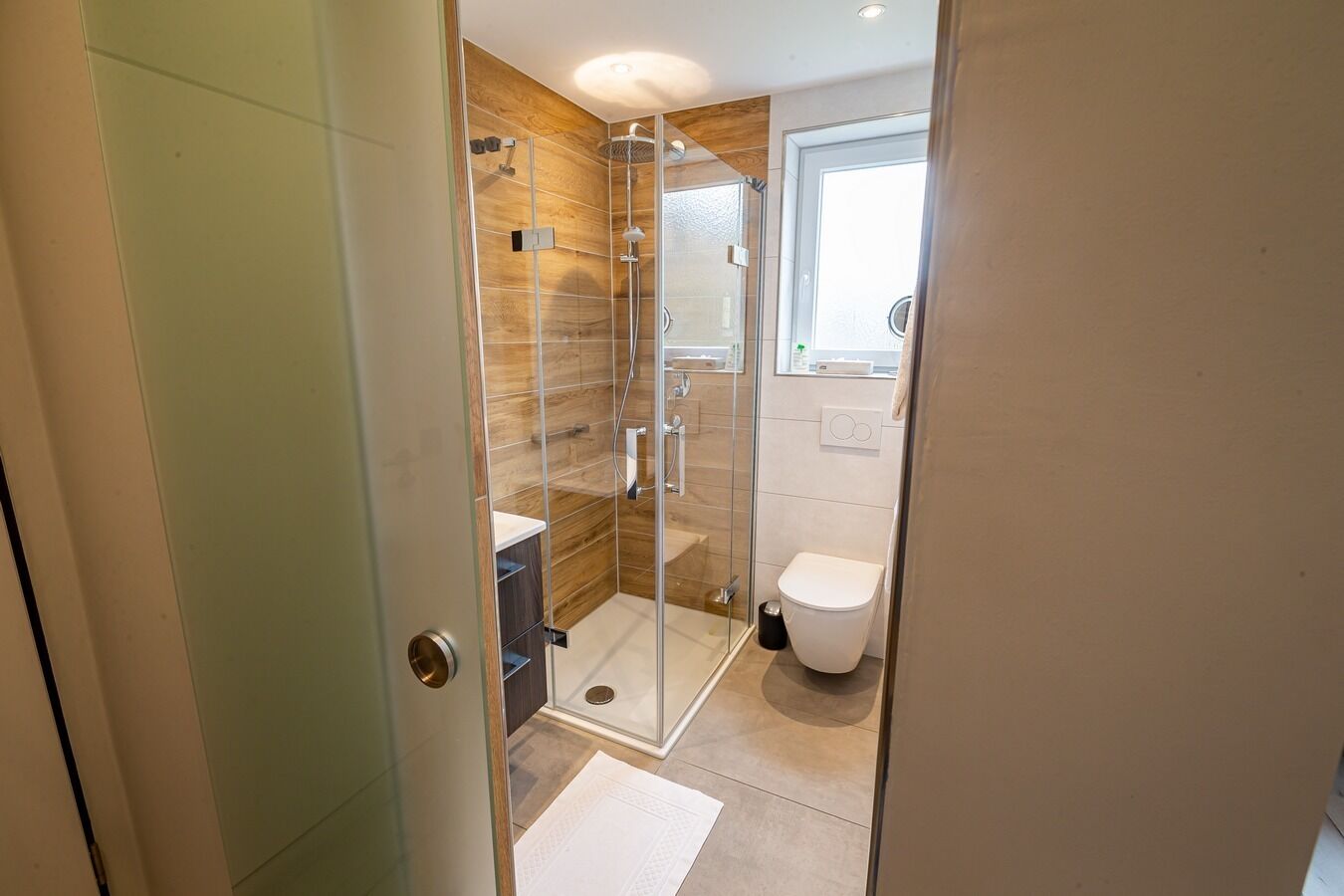 A modern bathroom with a glass-enclosed shower, a toilet, and a sink.