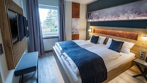 A modern hotel room with a large bed, a desk, a TV, and a window with curtains. - Hotel Hegenbarth's (Cochem)