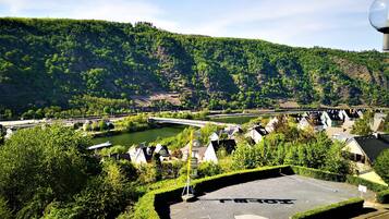 A scenic view of a riverside village with a bridge, lush greenery, and traditional houses.