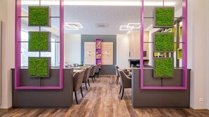 A modern office space with a central meeting area, wooden flooring, and green wall panels. - Hotel Hegenbarth's (Cochem)