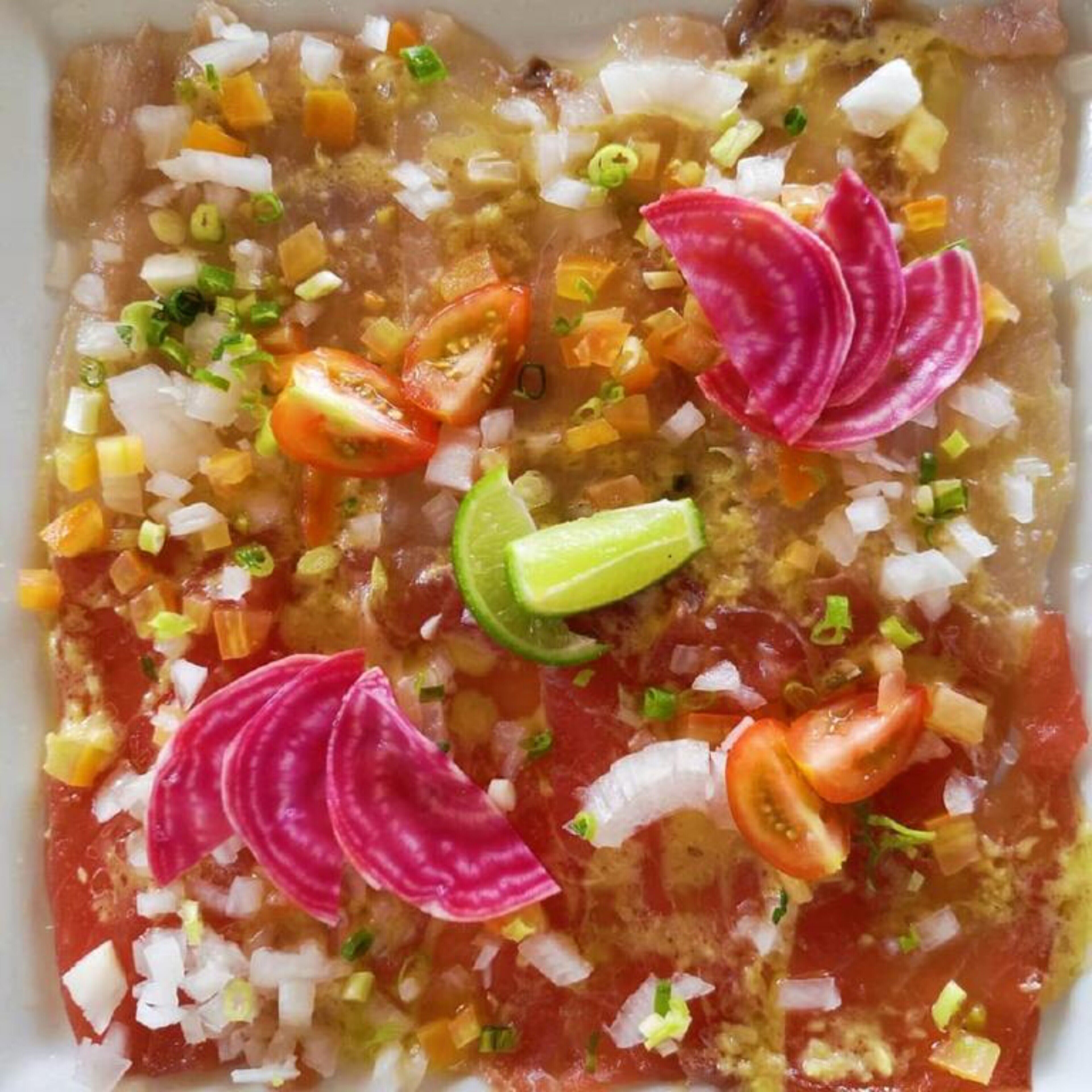 A dish with diced tomatoes, onions, and lime slices.