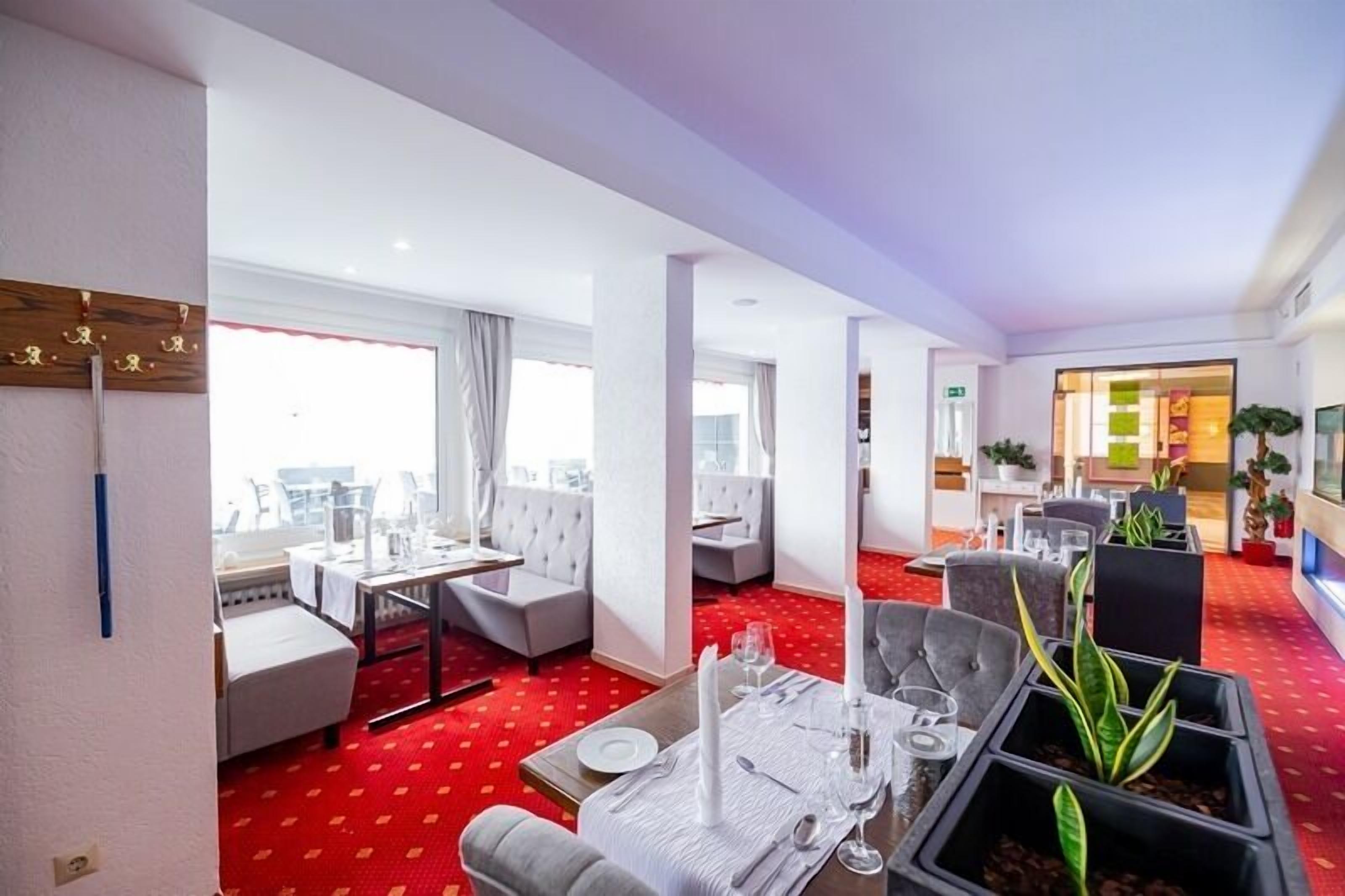A hotel lobby with a red carpet, seating areas, and a dining setup.