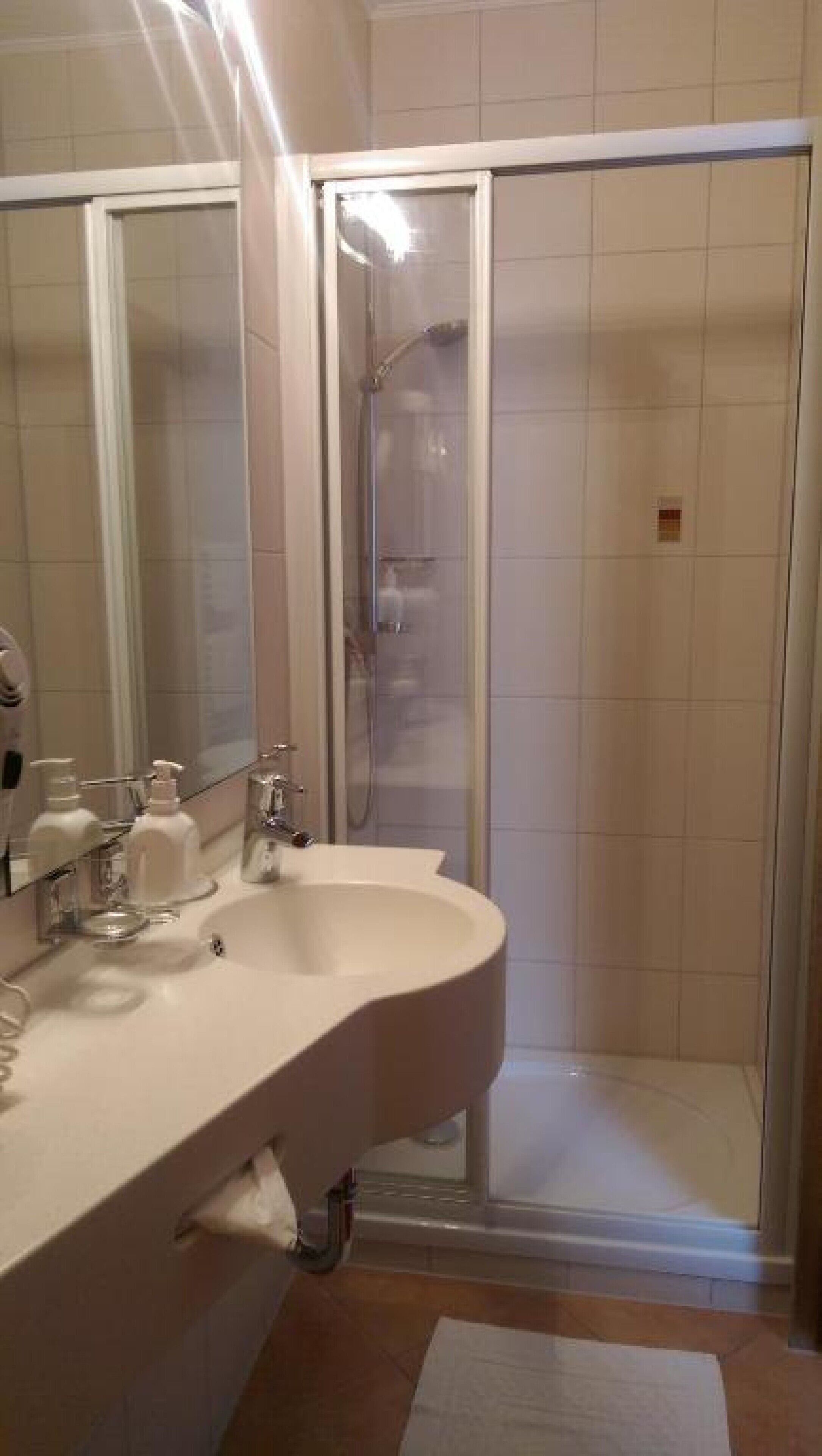 Un baño con lavamanos, espejo y ducha.