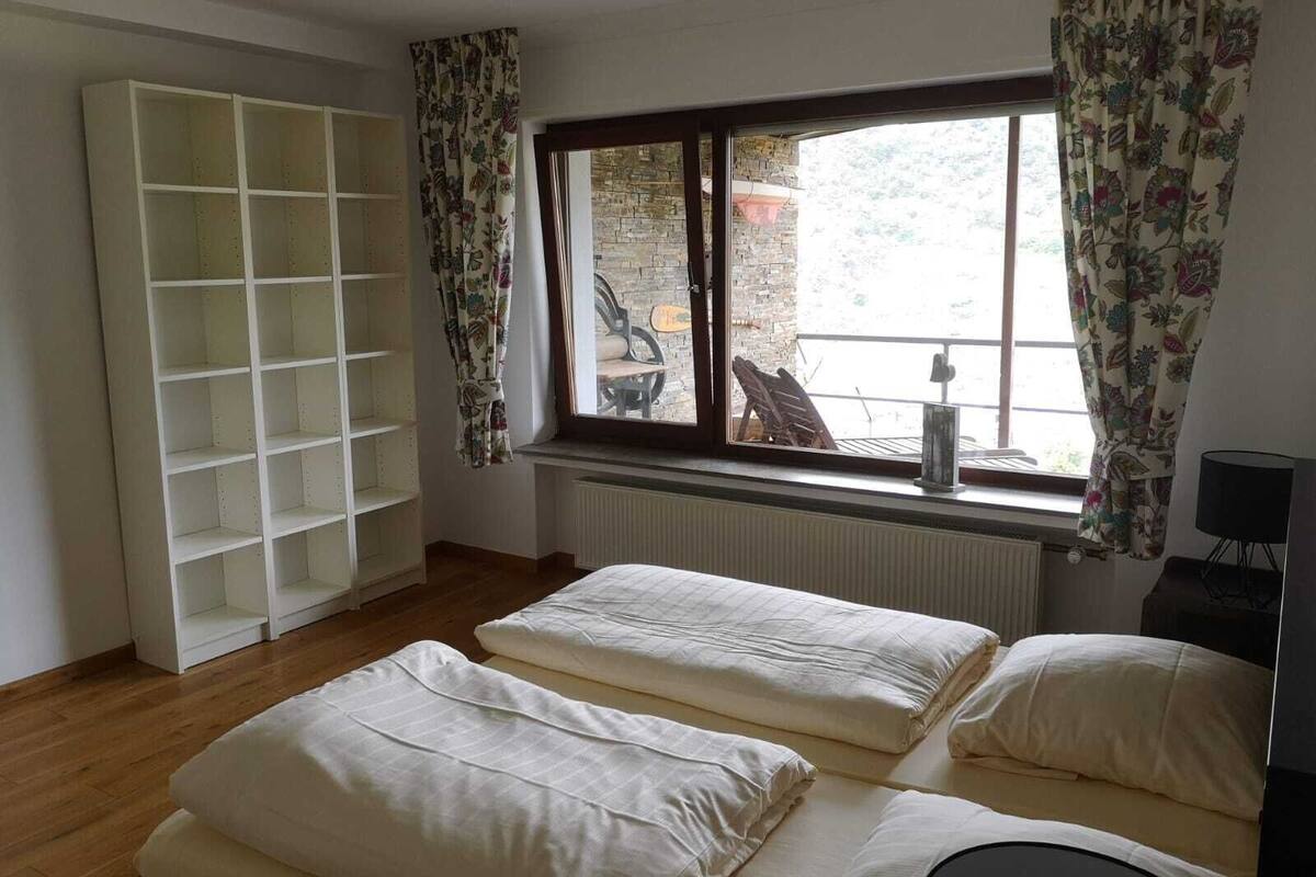 Una habitación con dos camas, un armario blanco, una ventana con cortinas y un radiador.