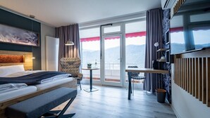 A modern hotel room with a bed, a desk, a chair, and a balcony with a view. - Hotel Hegenbarth's (Cochem)