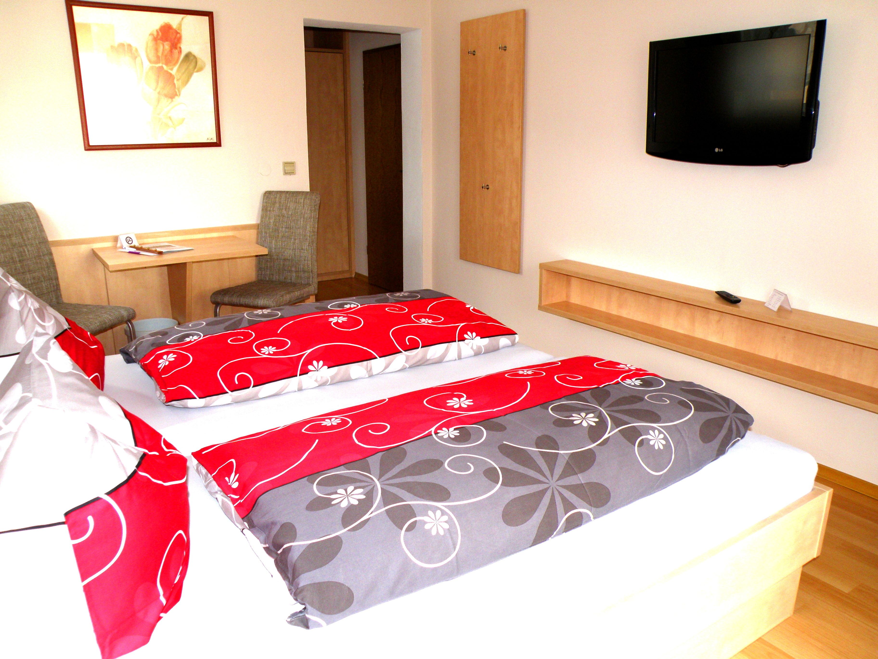 A hotel room with a bed, two chairs, a desk, a television, and a mirror.