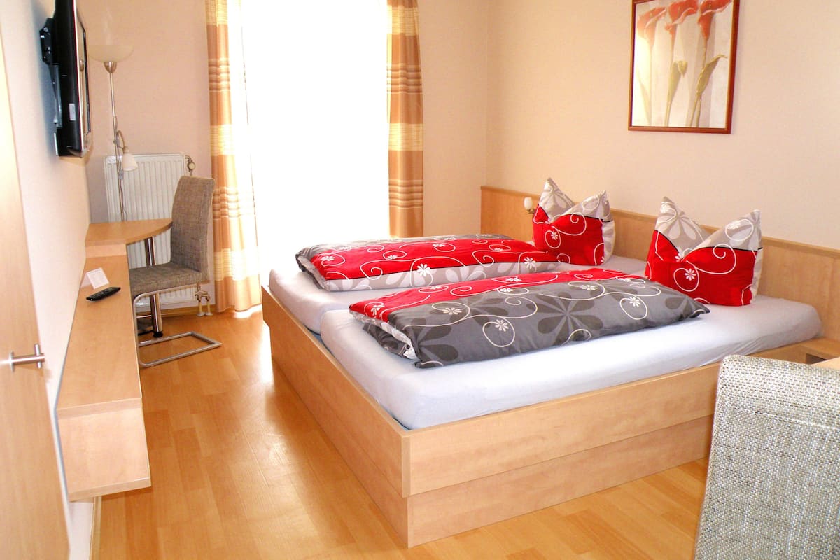 A hotel room with a bed, a desk, a chair, and a TV.