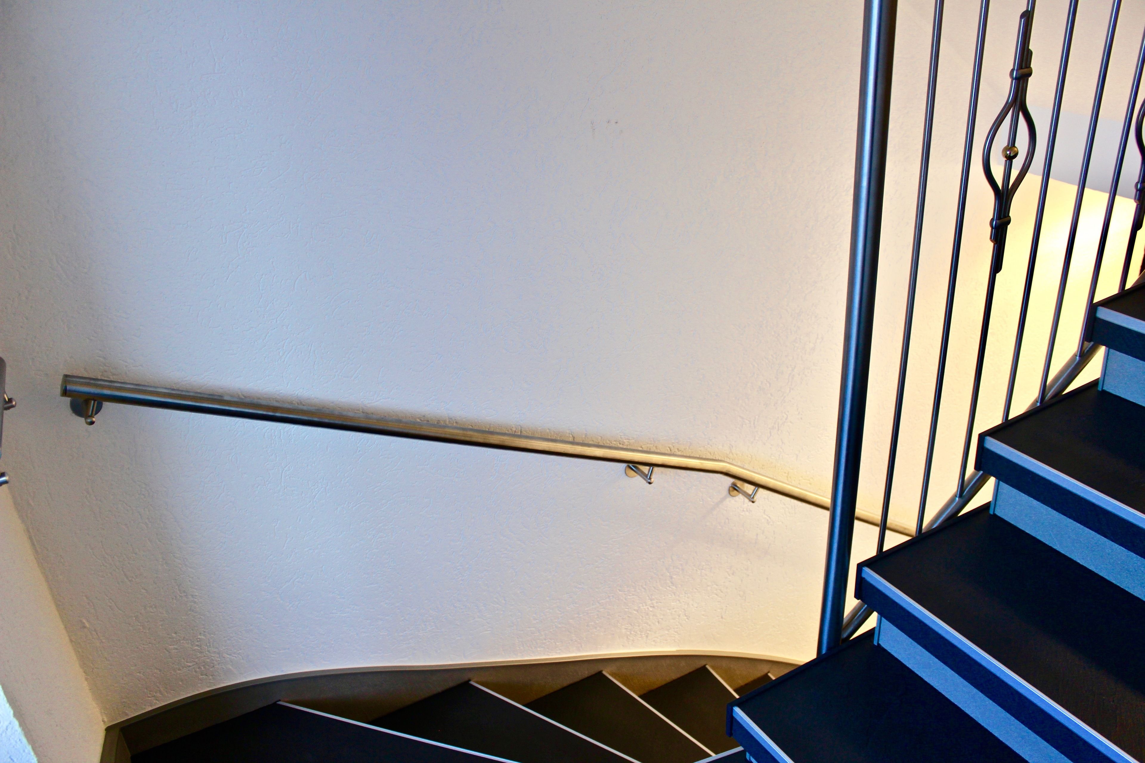 Una escalera curva con barandillas de metal y pasamanos.