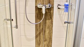A glass-enclosed shower with a wooden accent wall, a handheld showerhead, and a control panel.