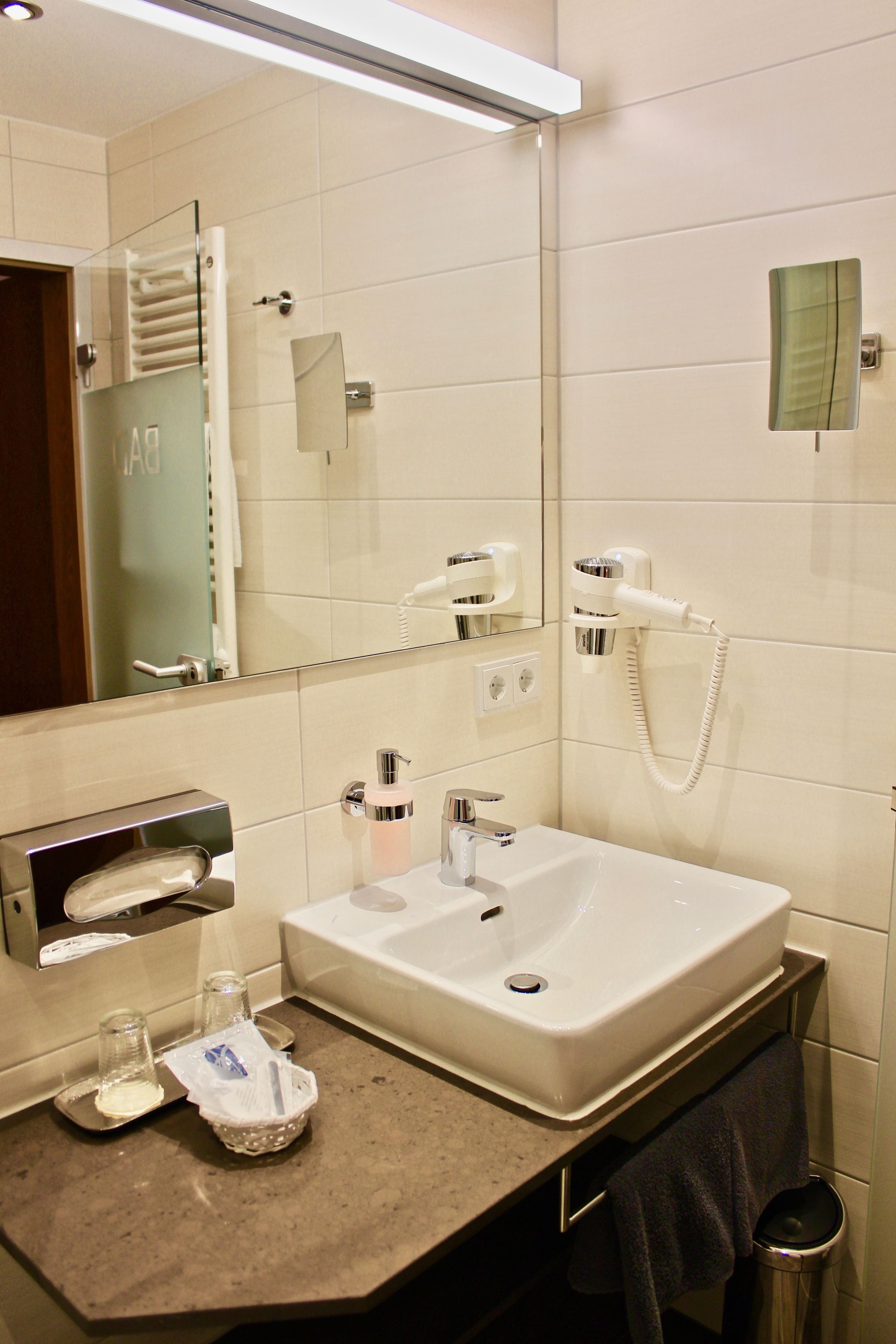 A bathroom with a sink, mirror, towel rack, and a hairdryer.