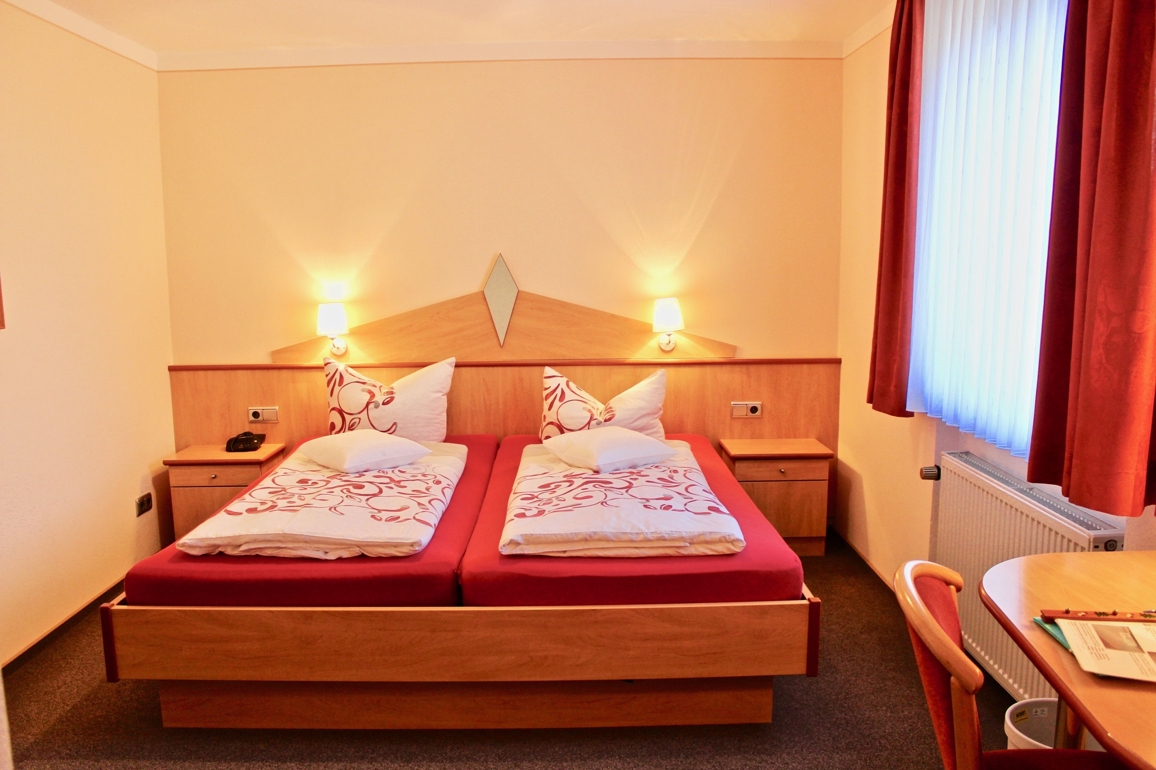 A hotel room with a double bed, two bedside tables, a desk, and a chair.