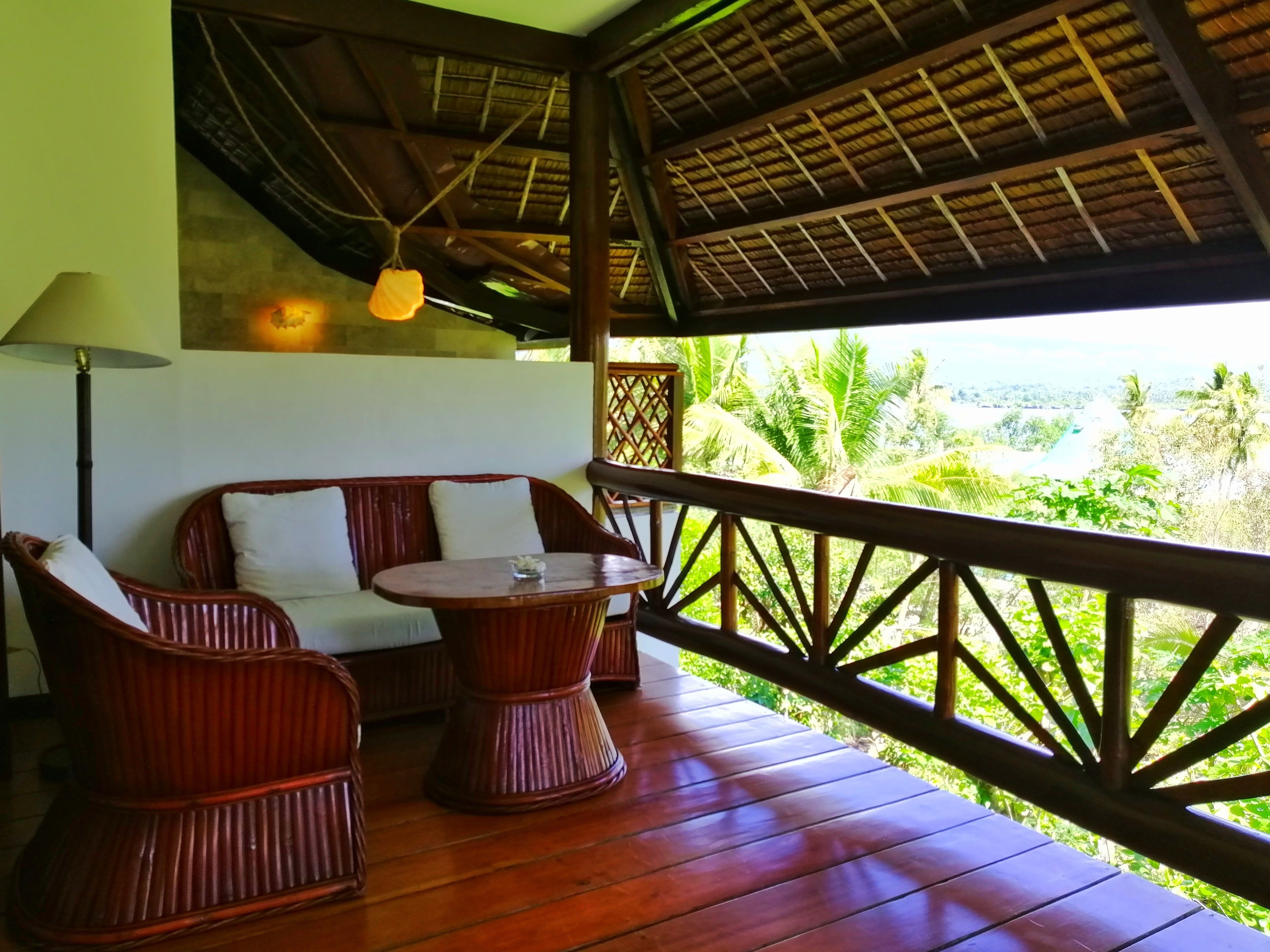 A wooden deck with wicker furniture, a table, and a hanging light fixture.