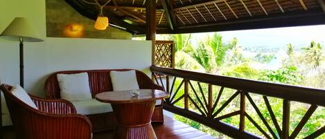 A wooden deck with wicker furniture, a table, and a hanging light fixture.