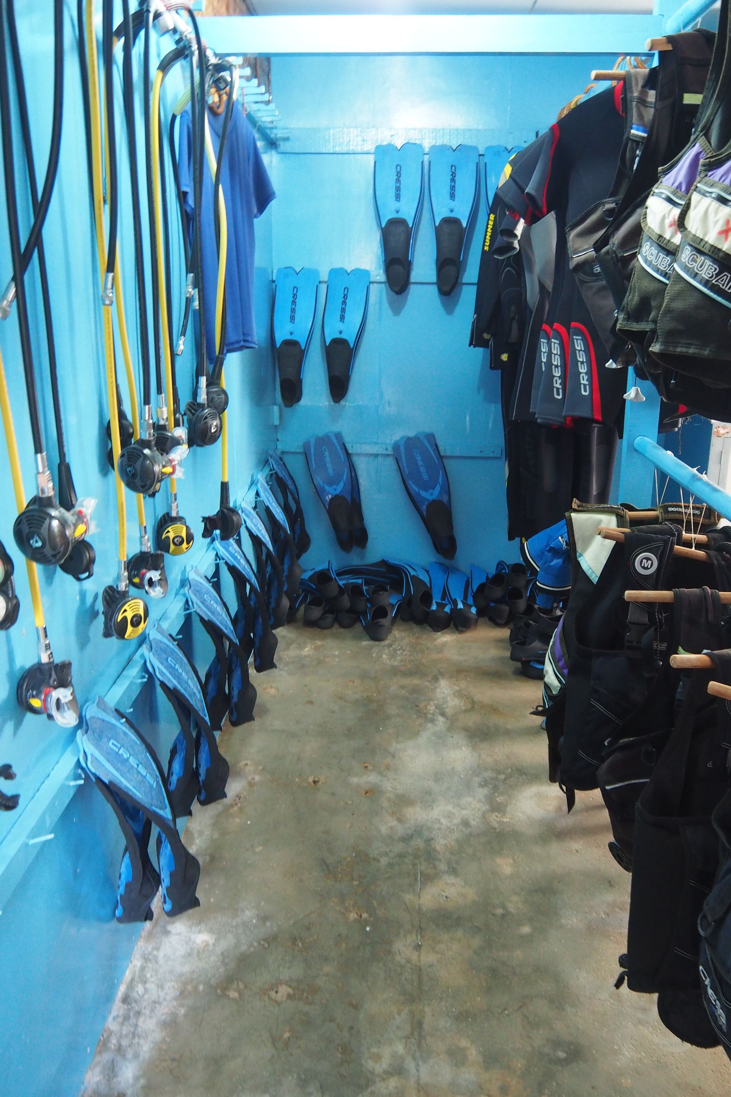 A diving locker with various diving equipment, including fins, masks, and wetsuits.