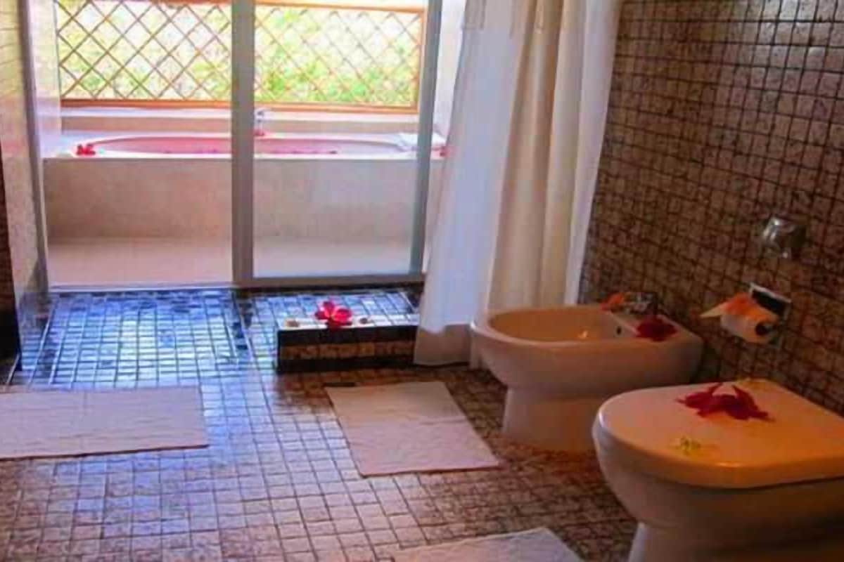 Une salle de bain avec deux toilettes, un espace douche et un sol carrelé.