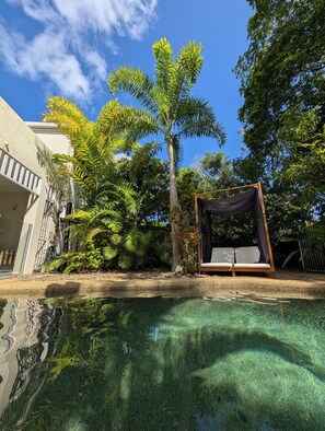 A clear swimming pool with a wooden deck and a lounge chair. - The Villas Palm Cove (Palm Cove)