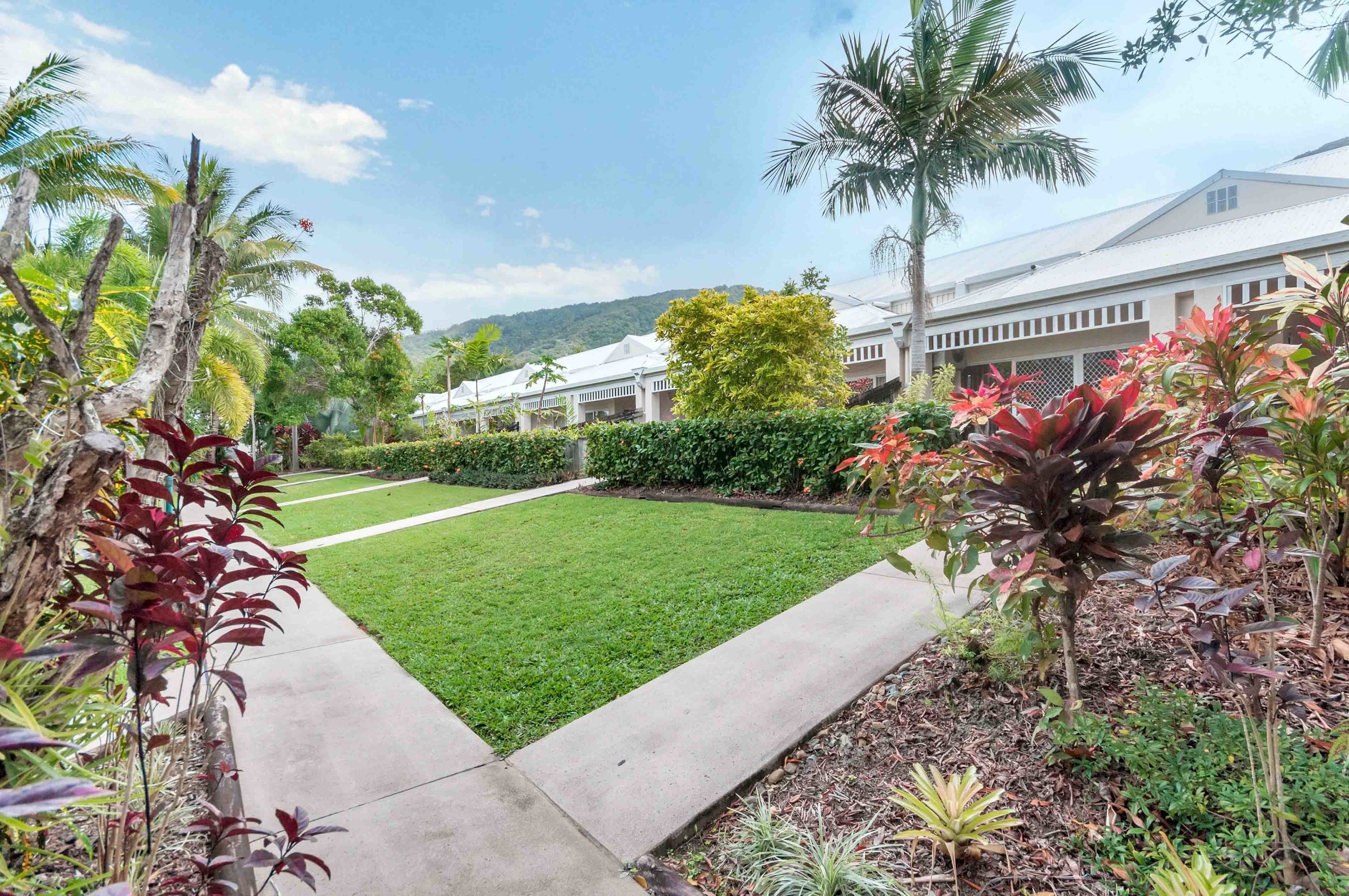 A well-maintained garden with a pathway leading to a building with multiple rooms.
