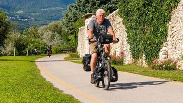A paved path with cyclists, surrounded by greenery and stone walls.