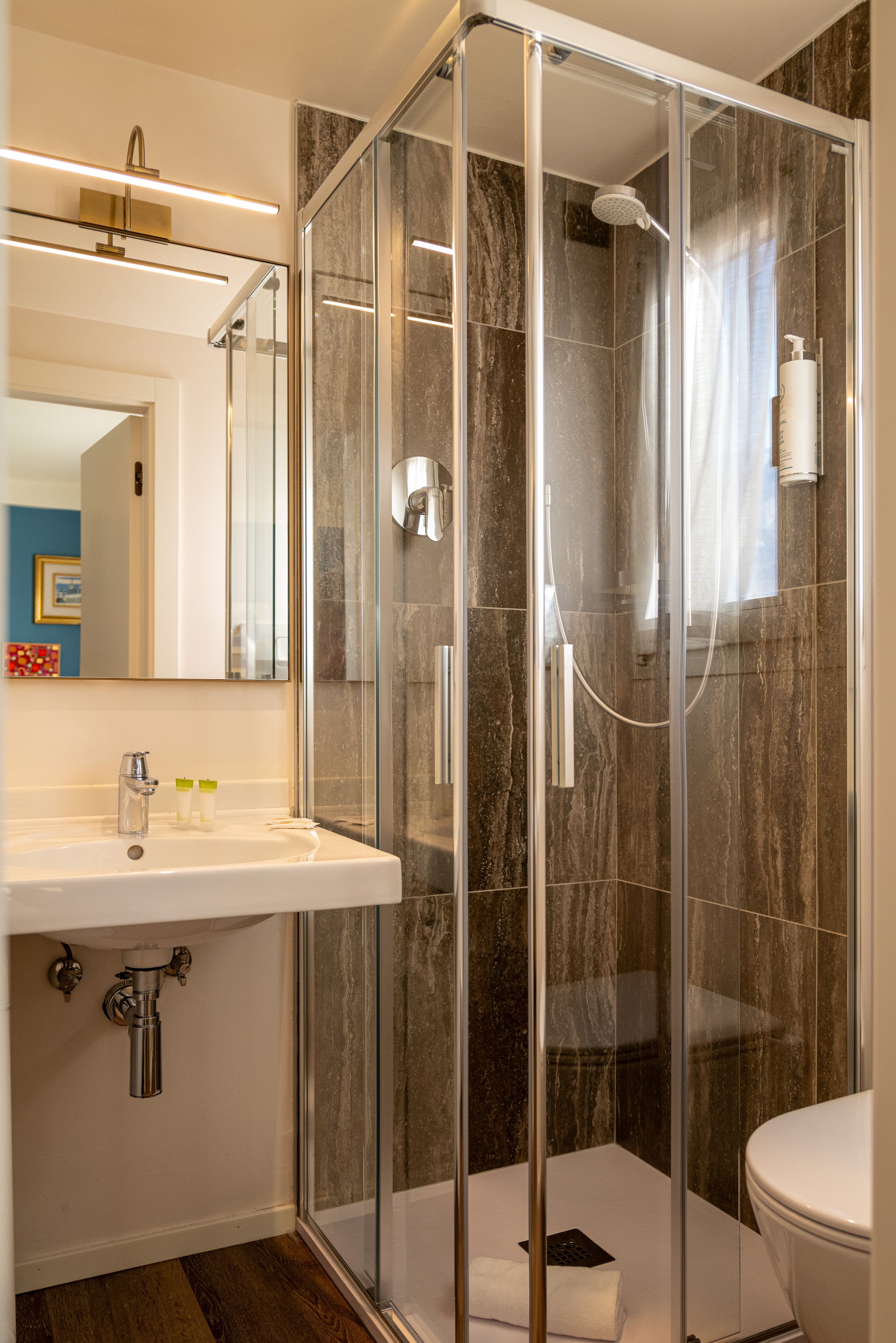 A modern bathroom with a glass-enclosed shower, a white sink, and a toilet.