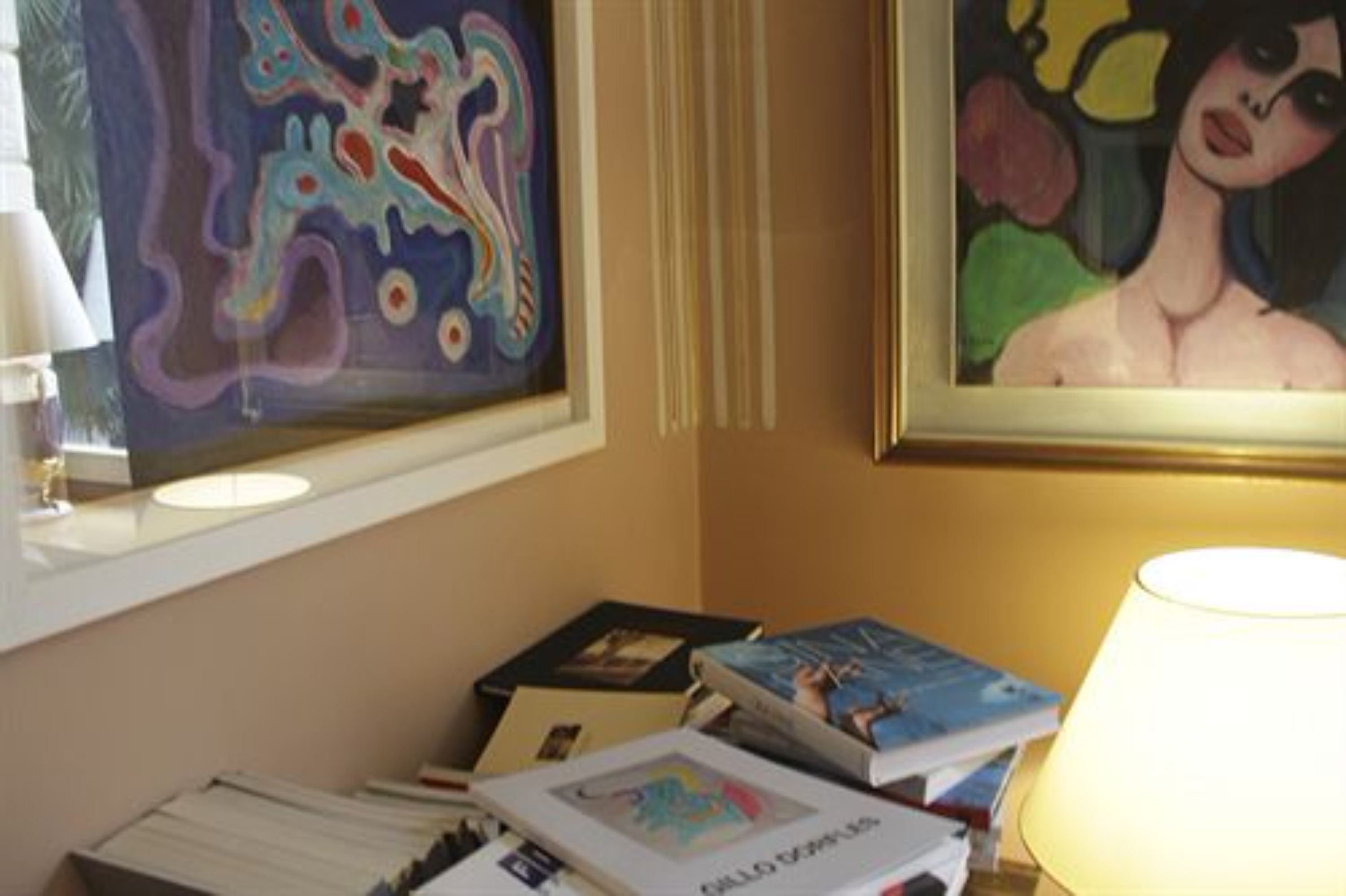 A room with a desk, books, and two paintings on the wall.